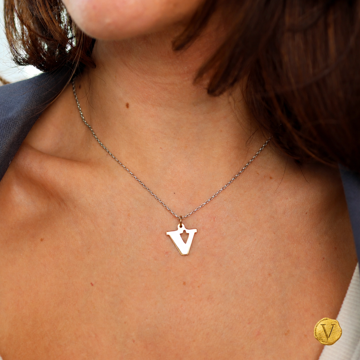 The 9ct yellow gold V pendant worn at the neckline with Victoire seal